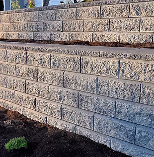 A beautiful view of a gray colored 2 tier retaining wall built with concrete blocks in ear